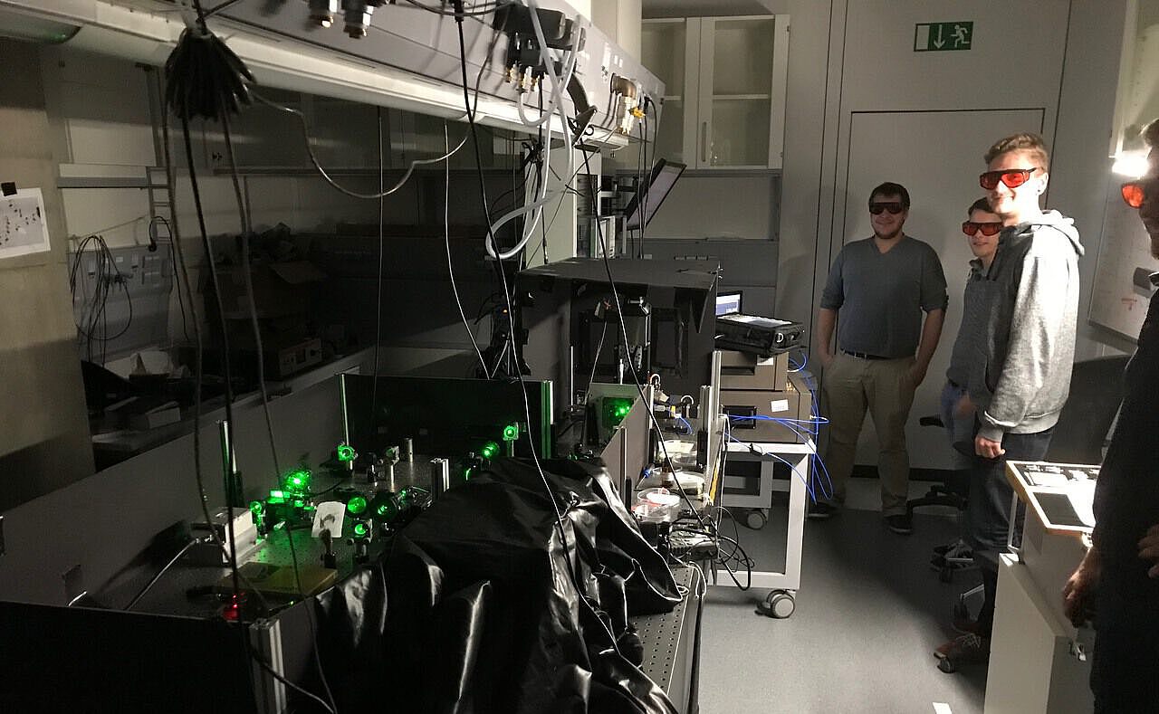 Studierende in einem Labor an einem Laser-Setup.
