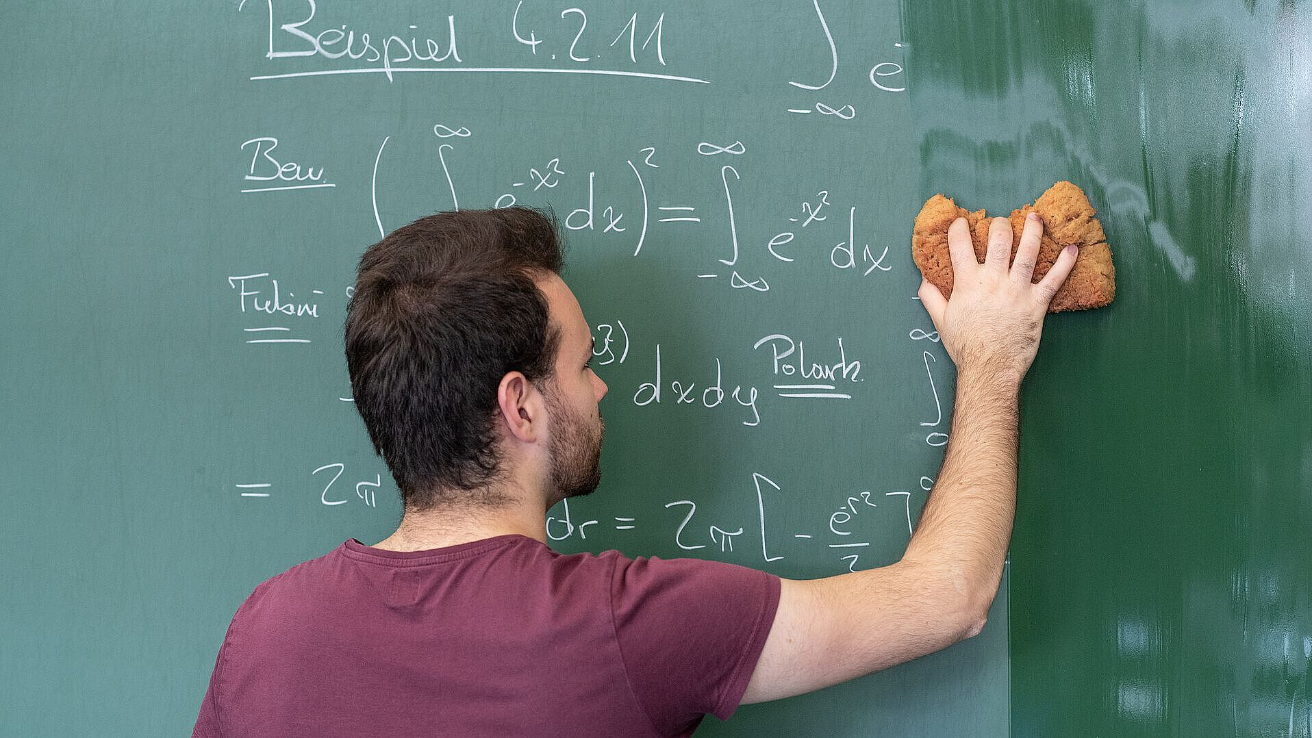 Dozent wischt die Tafel auf der mathematische Formeln stehen