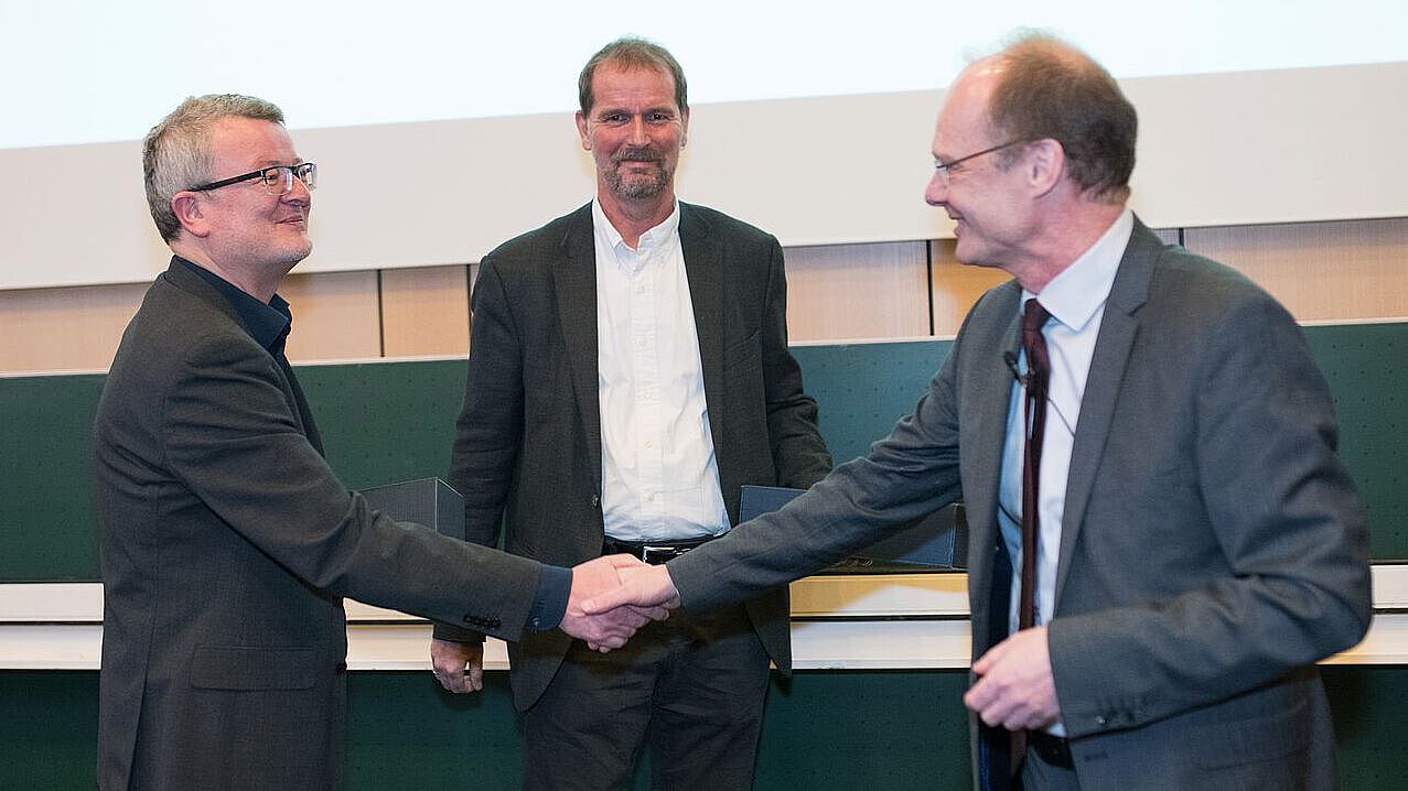 President Weber shaking hands and congratulating two leading scientists of Ulm University