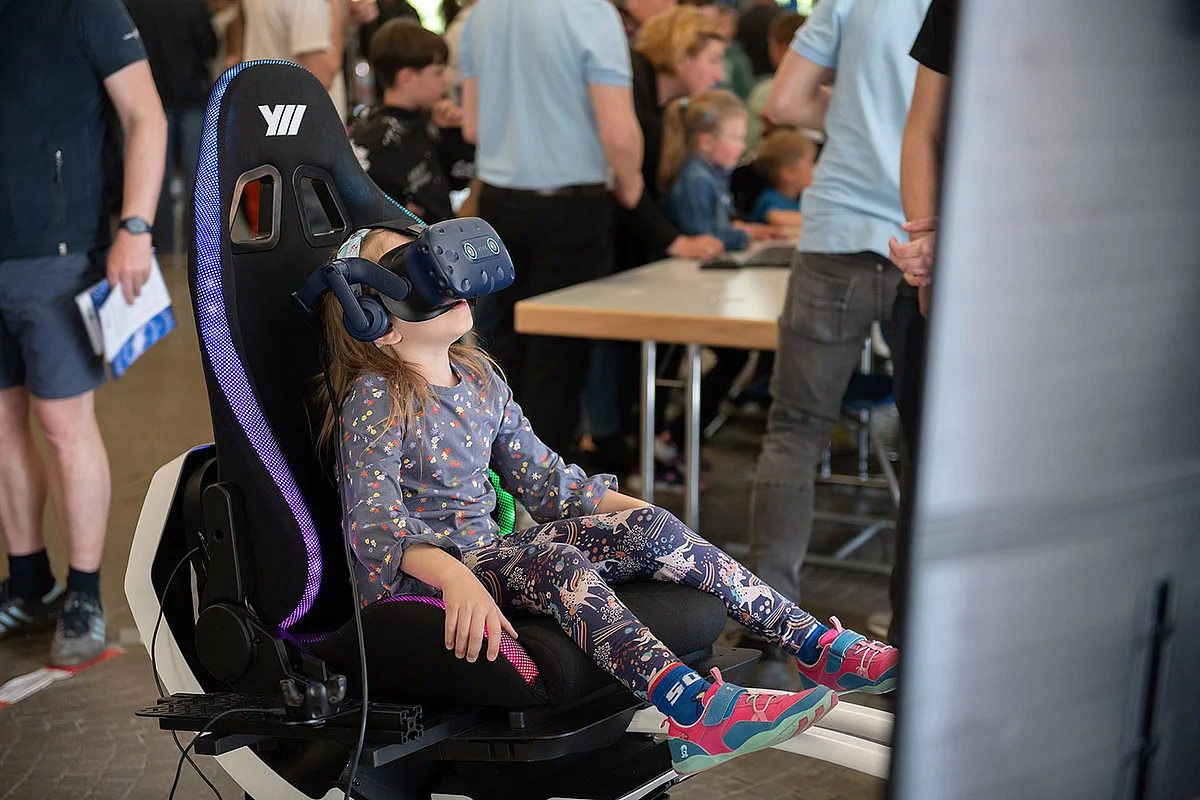 In einem Gaming-Stuhl sitzt ein Mädchen mit VR-Brille