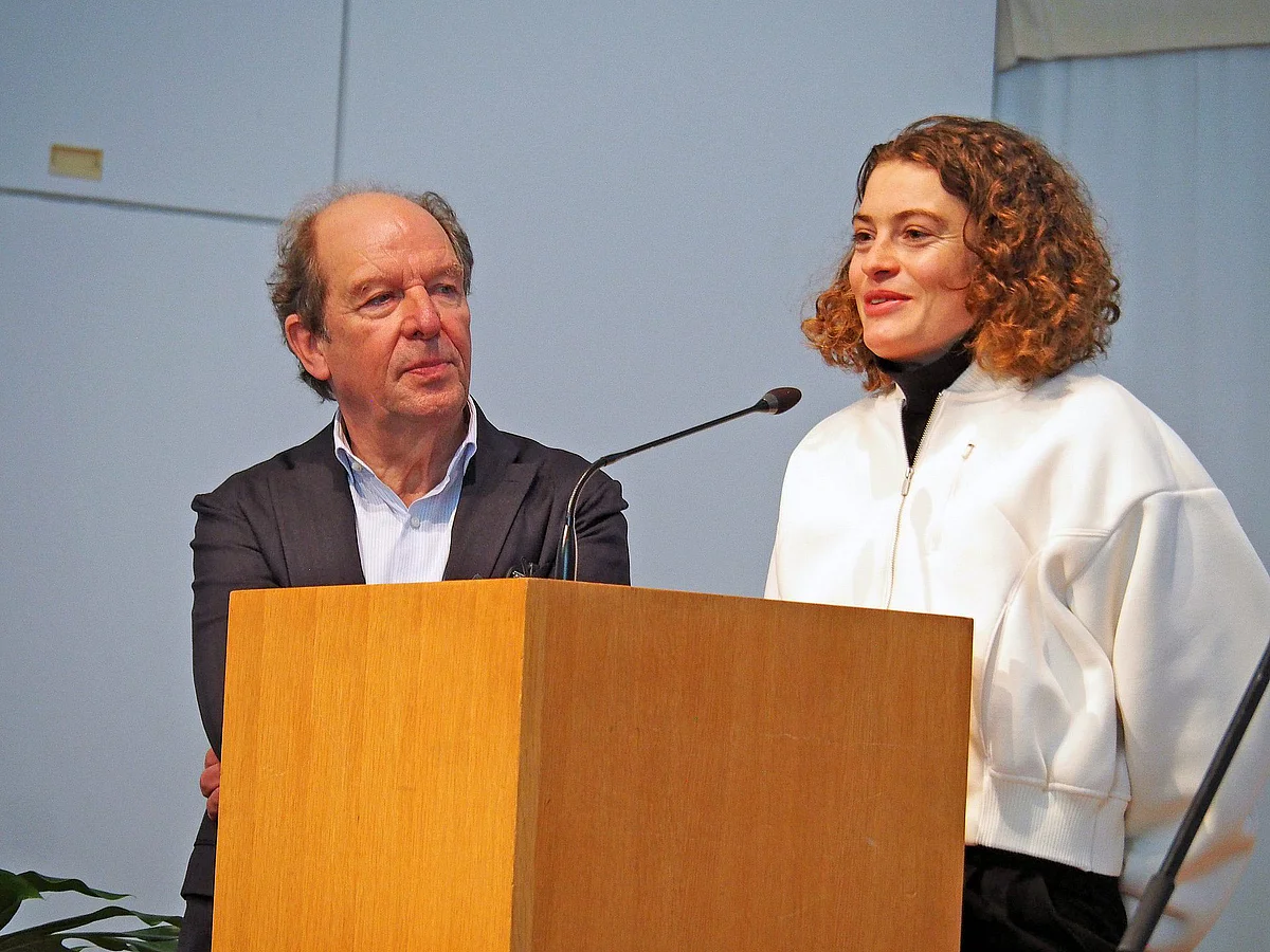 Alina Reh spricht an einem Pult in ein Mikrofon, links neben ihr steht Prof. Michael Debatin