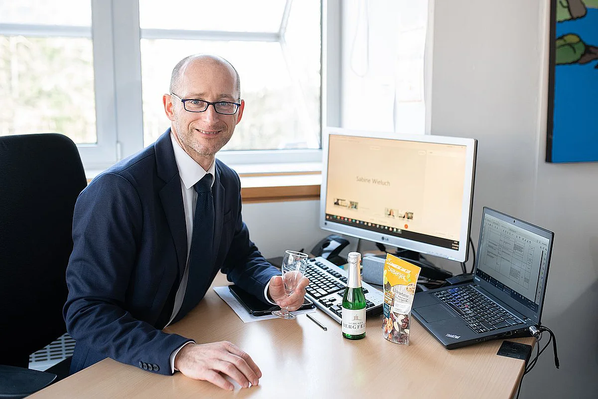 Prof. Dieter Rautenbach mit Sekt vor PC