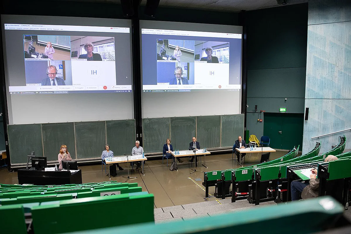 Personen im Hörsaal und auf der Leinwand diskutieren