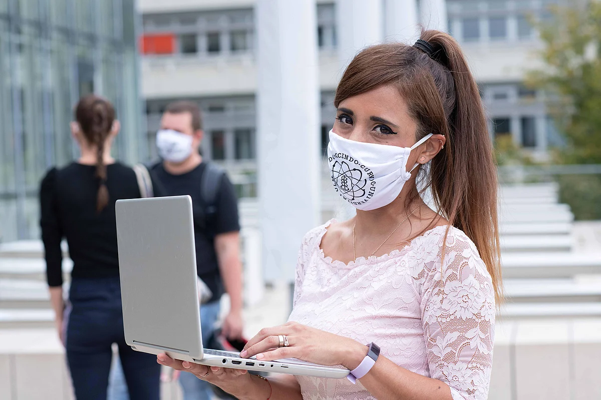 Studentin mit Maske und Laptop