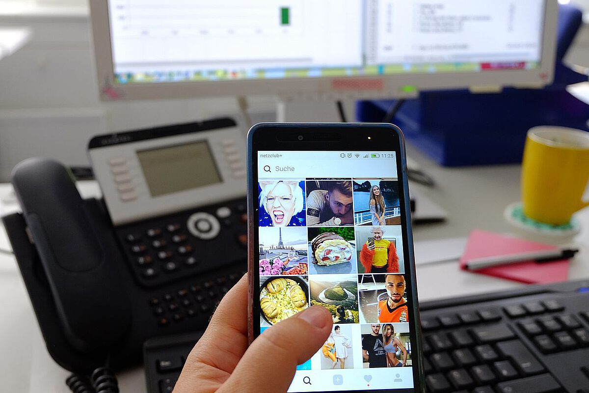 Smartphone mit Instagram-Feed am Arbeitsplatz