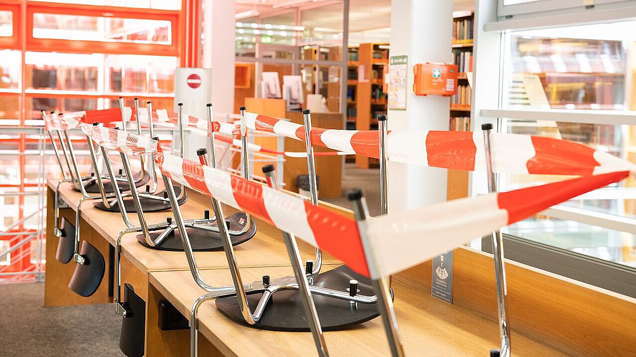 Bibliothek mit Absperrband gesperrte Sitzplätze in der Bibliothek