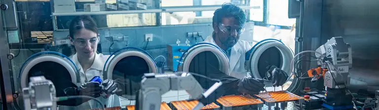 Forschende der Universität Ulm bereiten in den Handschuhboxen einer Robotikstrecke Komponenten für den Zusammenbau von Batterien vor