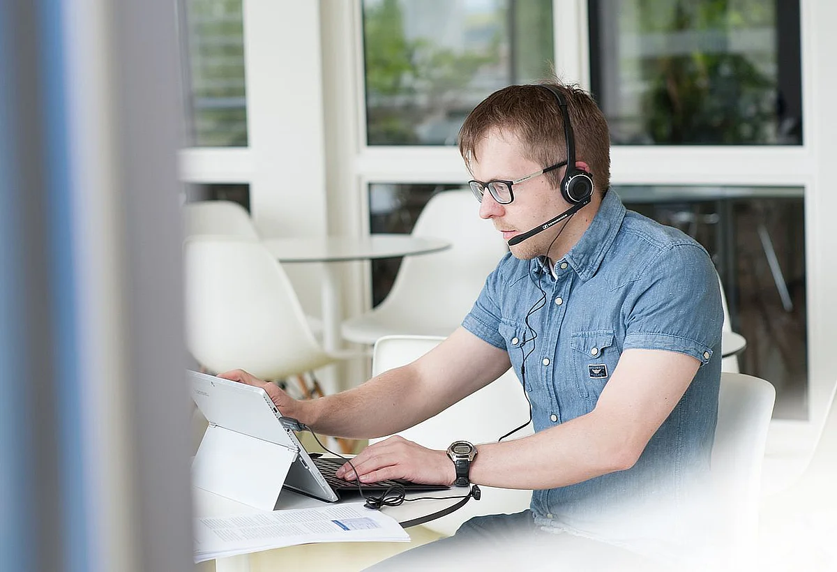 Mann am Laptop mit Headset