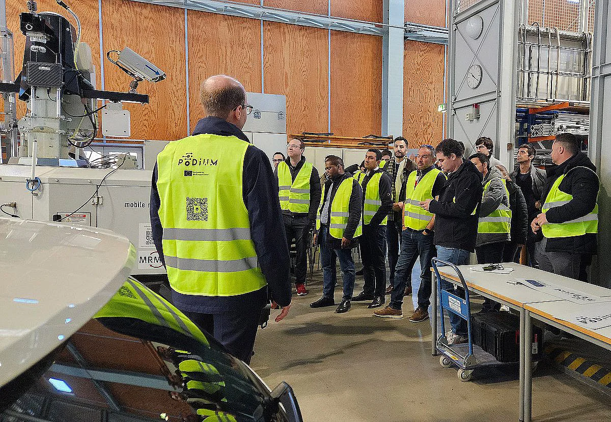 Die Projektpartner besichtigen die mobile Infrastruktursensorik und die Testfahrzeuge in der Halle des Instituts für Mess-, Regel- und Mikrotechnik