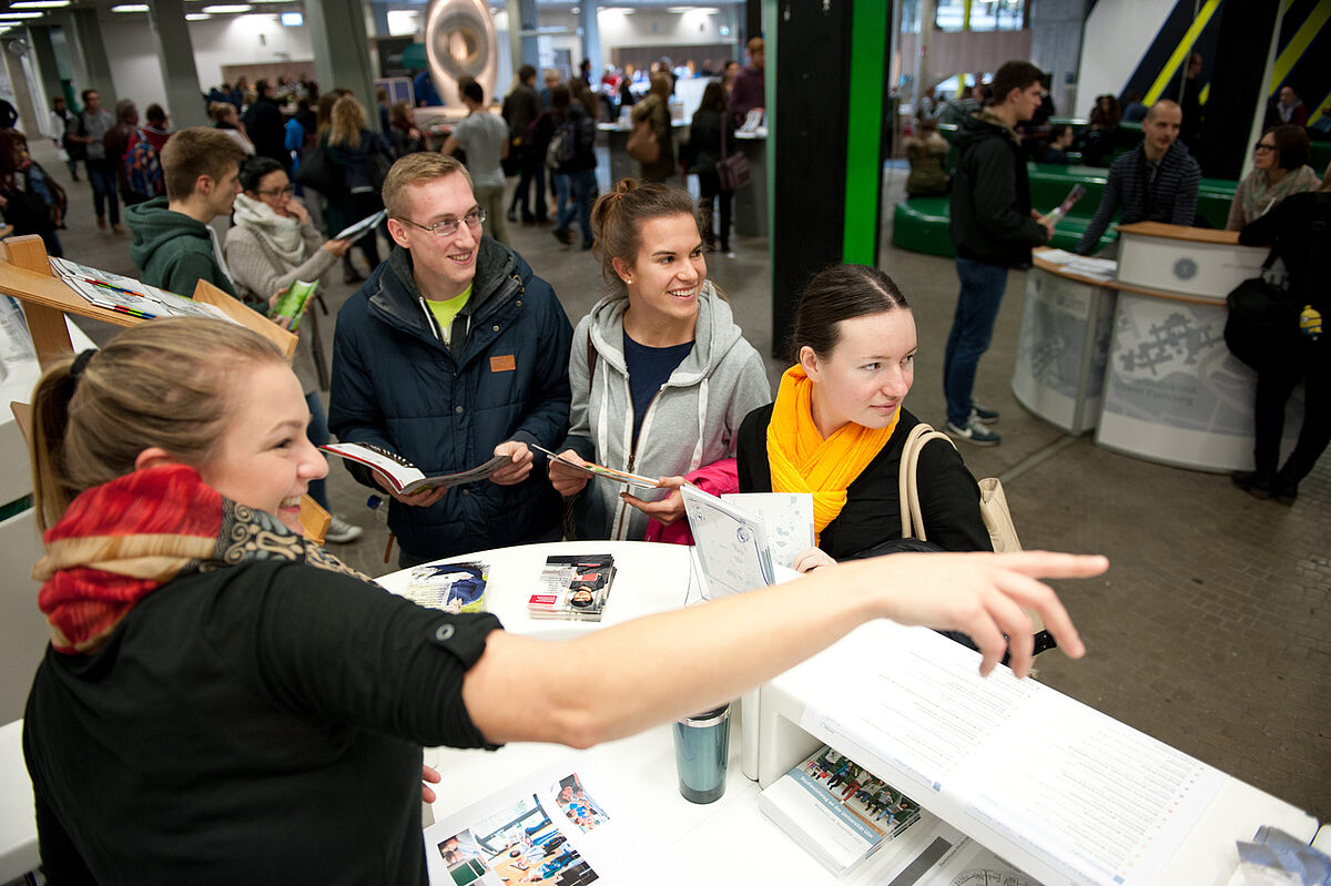 (Foto: Elvira Eberhardt / kiz): „Hier entlang zum Wunschstudium“ hieß es schon beim Studieninfotag 2015 an der Uni Ulm. An zahlreichen Infoständen beantworten auch dieses Mal wieder Studienberaterinnen alle Fragen rund um die verschiedenen Studieng