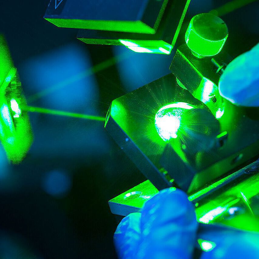 Bild eines grünen Laserstrahls welcher auf ein Prisma trifft