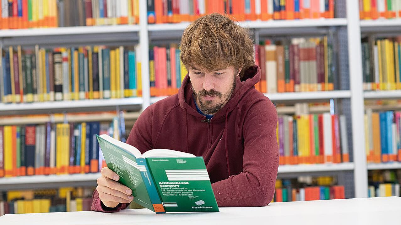 Lucas liest ein Buch in der Bibliothek