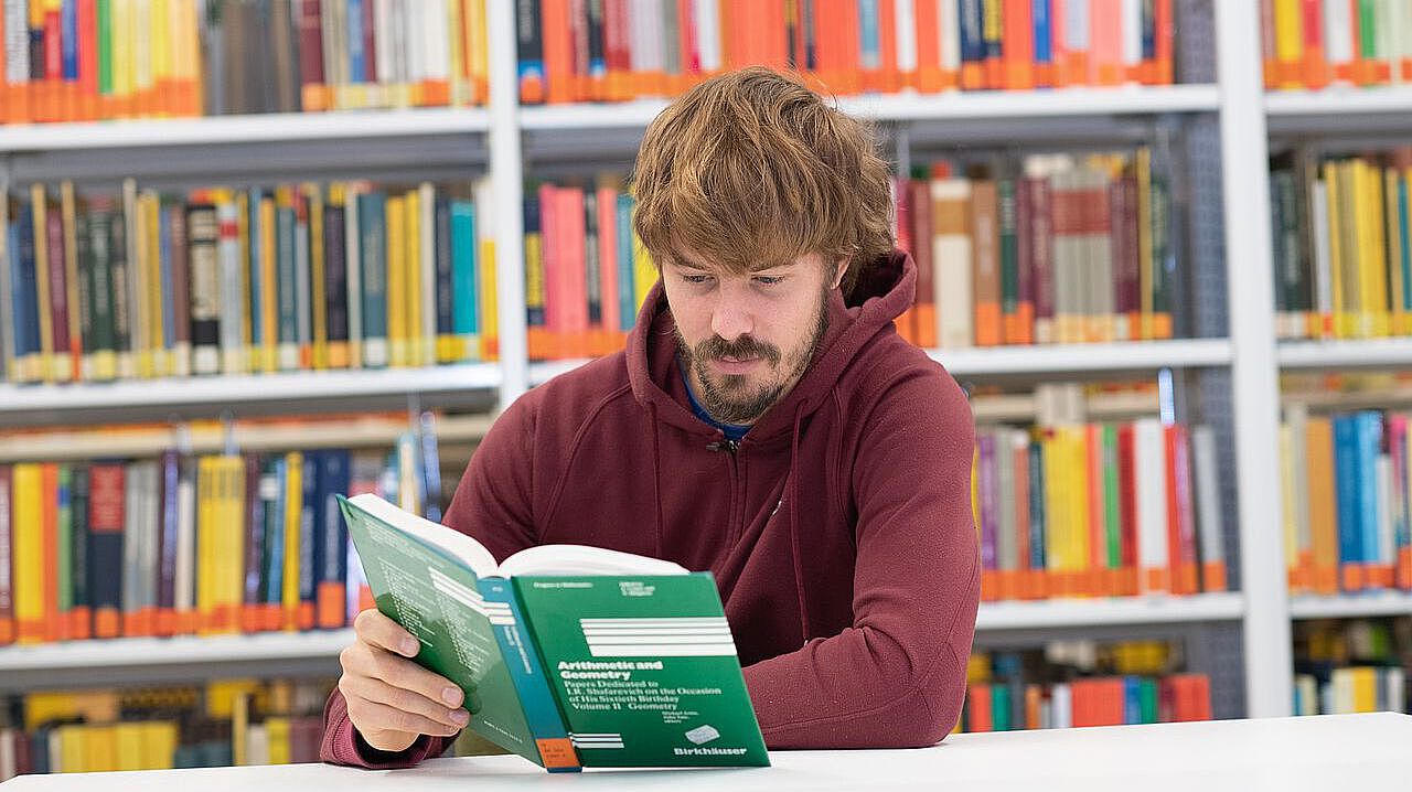 Student liest ein Mathematisches Buch in der Bibliothek