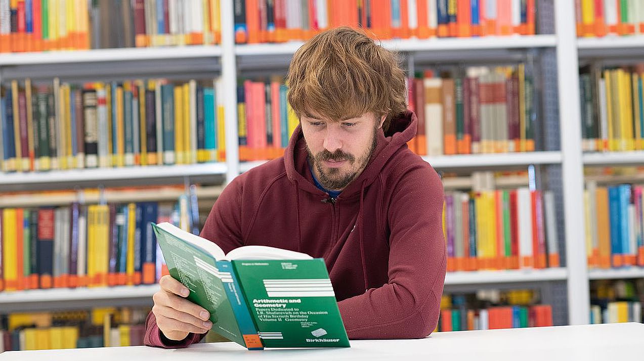 Student sitzt in der Bin und liest ein mathematisches Buch Student sitzt in der Bin und liest ein mathematisches Buch