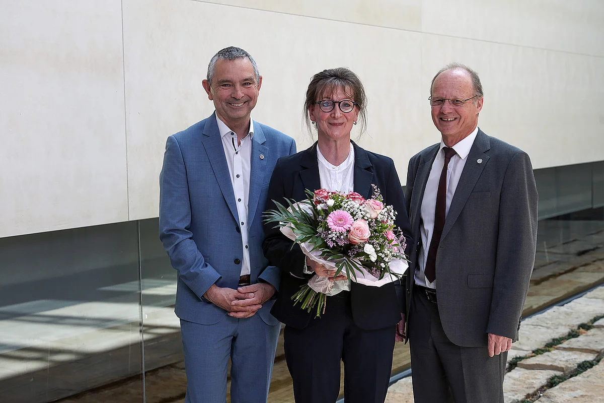 Gruppenbild, von links: Prof Michael Kühl, Dr. Wiltrud Christine Radau mit Blumenstrauß in der Hand, Prof. Michael Weber