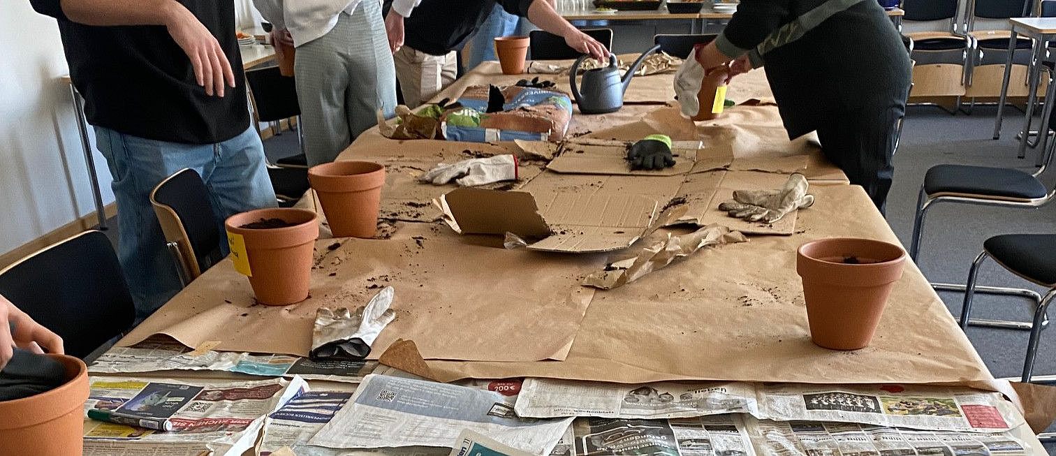 Junge Menschen befüllen Blumentöpfe mit Erde