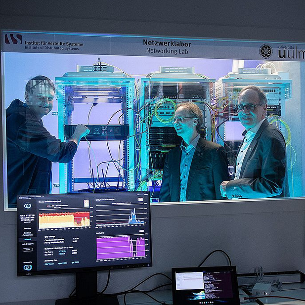 Kevin Füchsel (left) simulates a hacking attempt in the lab; Matthias Zimmermann (DLR) and Joachim Ankerhold observe