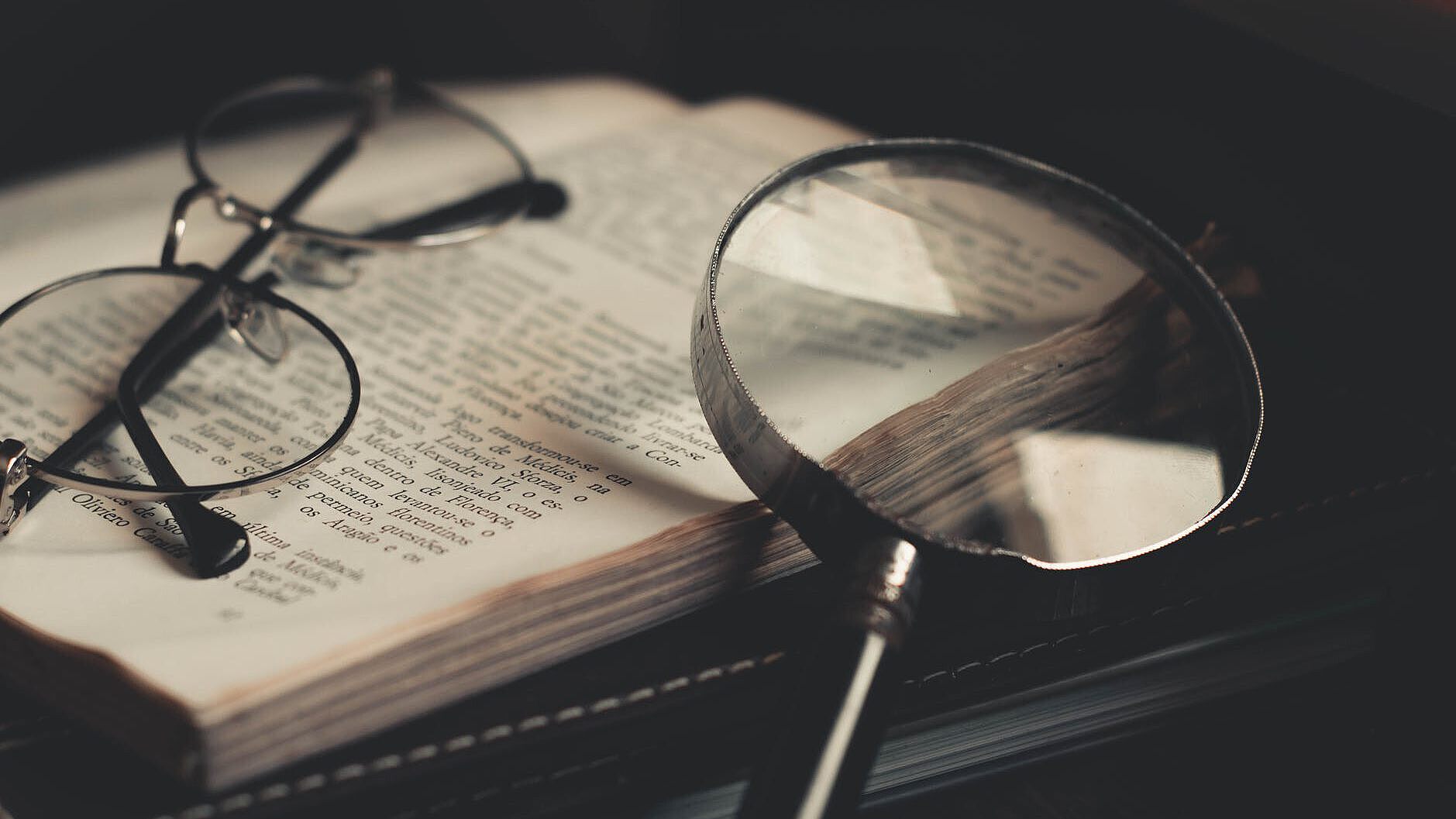 Aufgeschlagenes Buch mit Brille und Lupe Aufgeschlagenes Buch mit Brille und Lupe