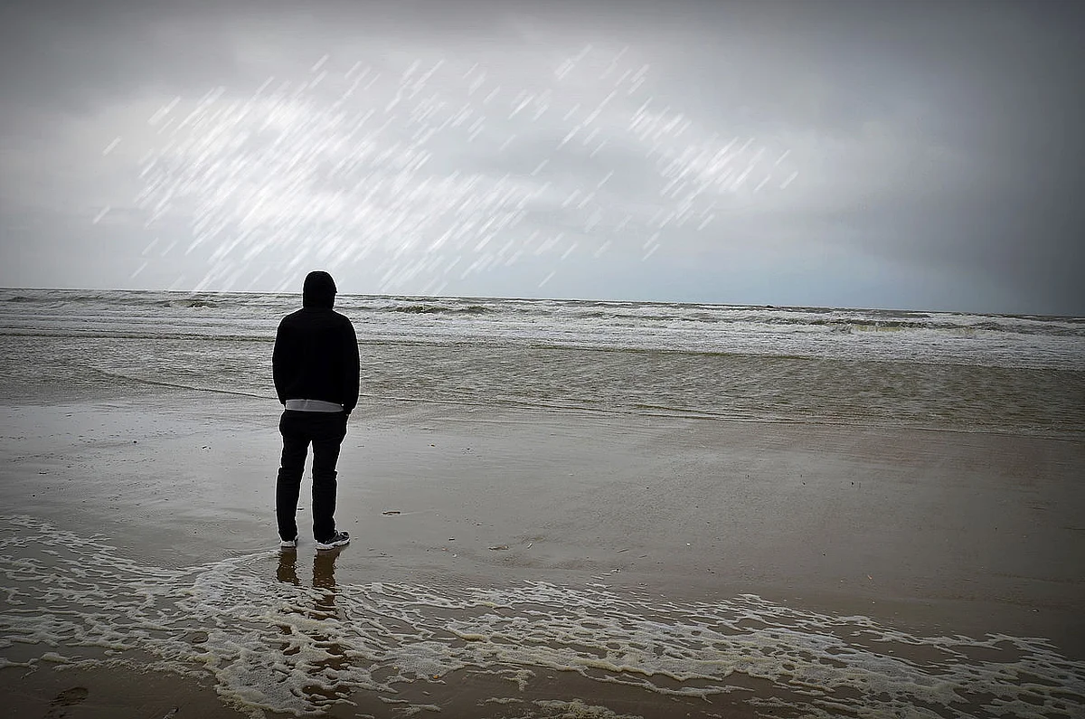 Ein Mensch steht am Strand und schaut auf das Meer 