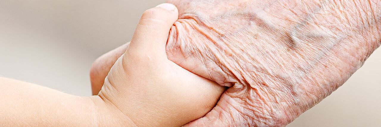 Jung und alt Kind und ältere Person halten Händchen