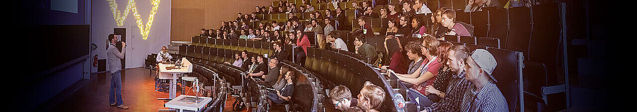 Ein Foto der Veranstaltung "Streiflicht 2019". Studierende in einem Hörsaal, die dem Moderator zuhören.