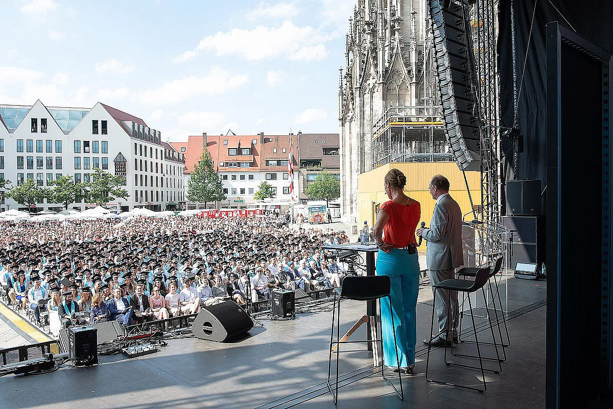 Presenter Dr Denise Burgert and Ulm University President Professor Michael Weber look out from the stage onto Münsterplatz