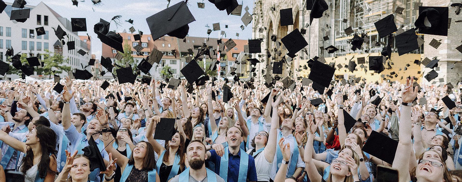 Graduates throw hats at the academic graduation ceremony on Ulm's Münsterplatz