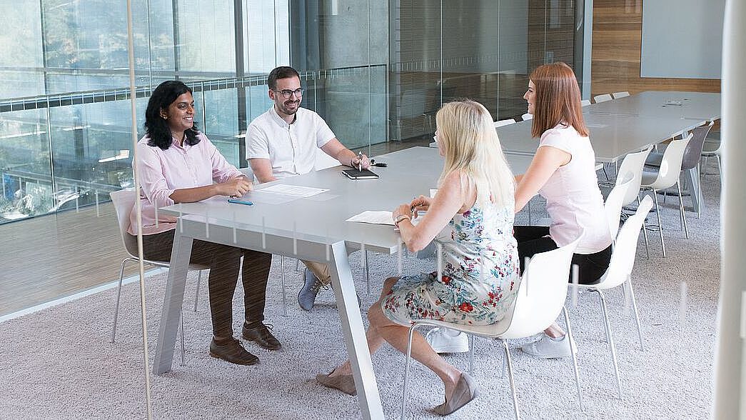 Vier Beschäftigte sitzen an einem Konferenztisch.