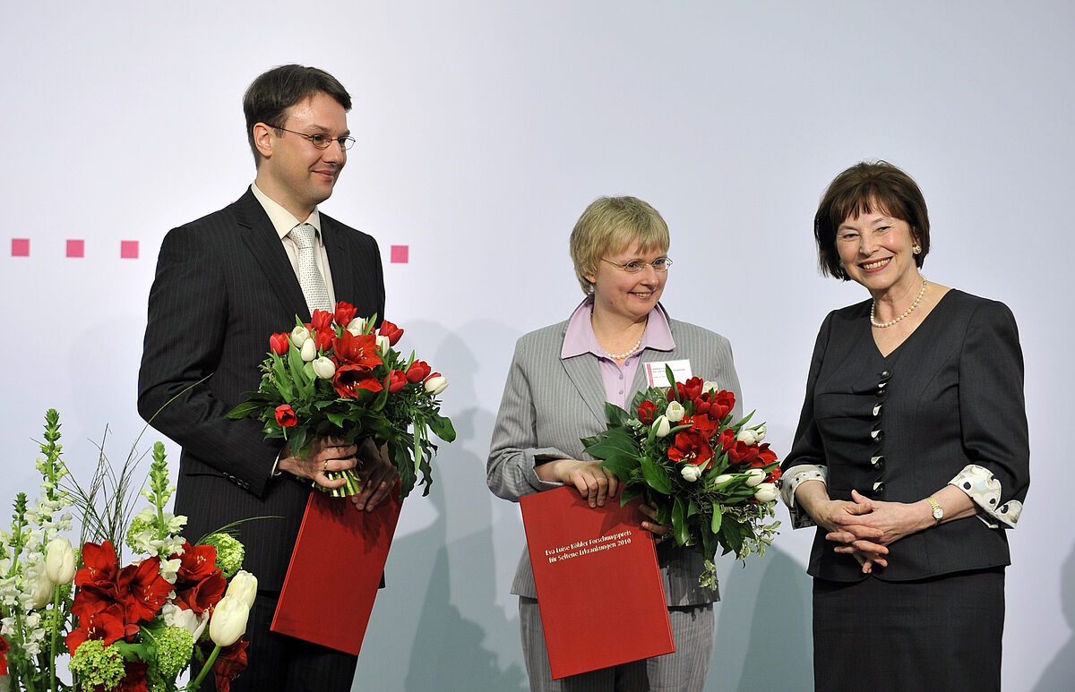 Eva Luise Köhler (re) gratuliert den Preisträgern des Eva Luise und Horst Köhler Forschungspreises Karin Jurkat-Rott und Marc-Andre Weber