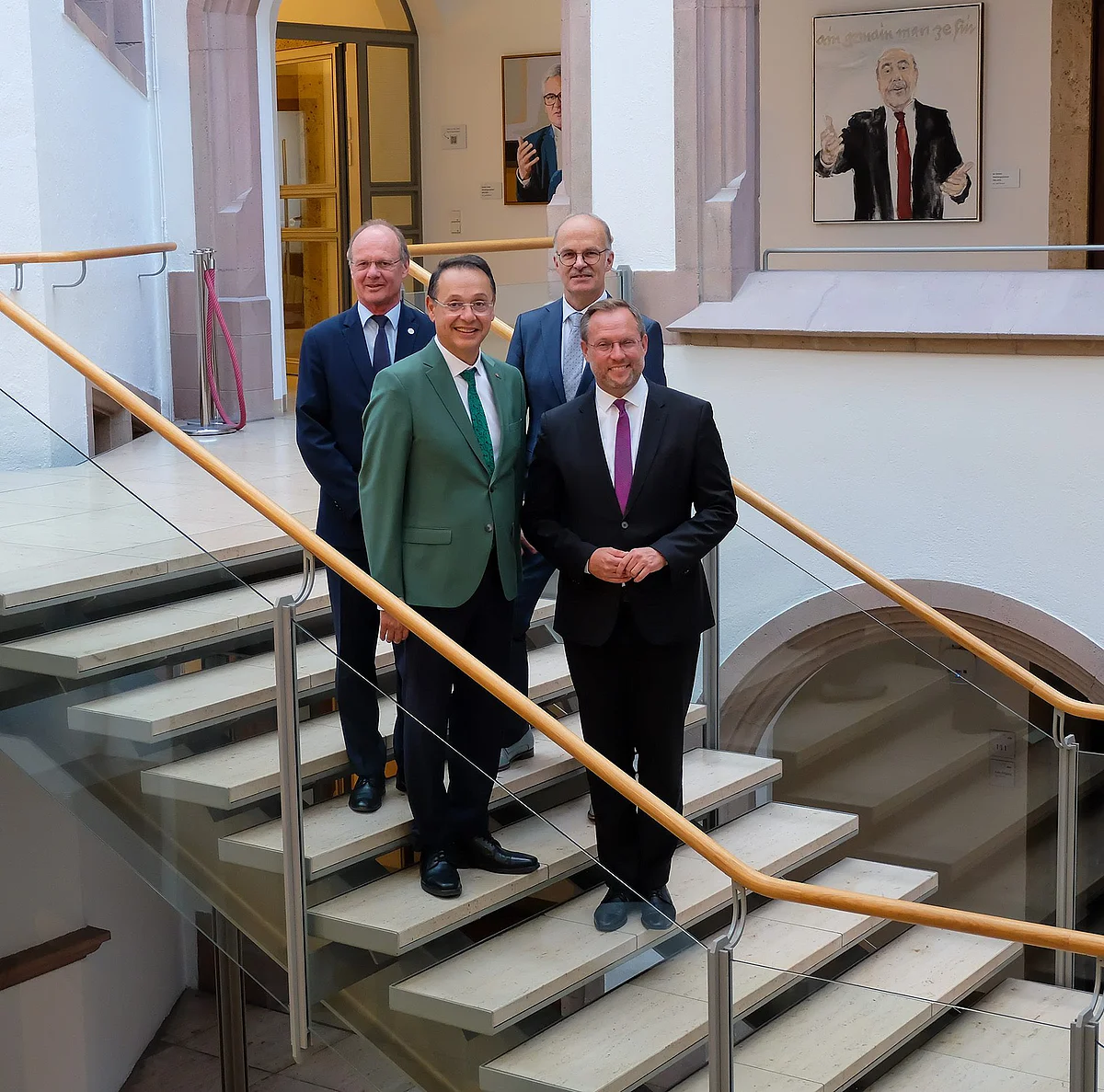Prof. Michael Weber, Prof. Ashraf Mansour, Prof. Volker Reuter und Oberbürgermeister Martin Ansbacher stehen auf einer Treppe im Rathaus und lächeln