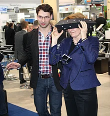 Blick mit ImmerSight in die dreidimensionale virtuelle Welt: Fabian Weiss, einer der drei beteiligten Ulmer Nachwuchswissenschaftler, erklärt einer Interessentin auf der CeBIT die neu entwickelte 3D-Technologie 