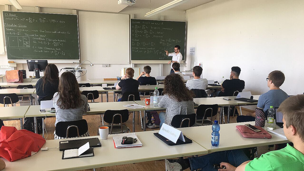 Studierende sitzen gemeinsam mit Schüler*innen im Seminarraum zu Vorlesungen an der Uni Ulm