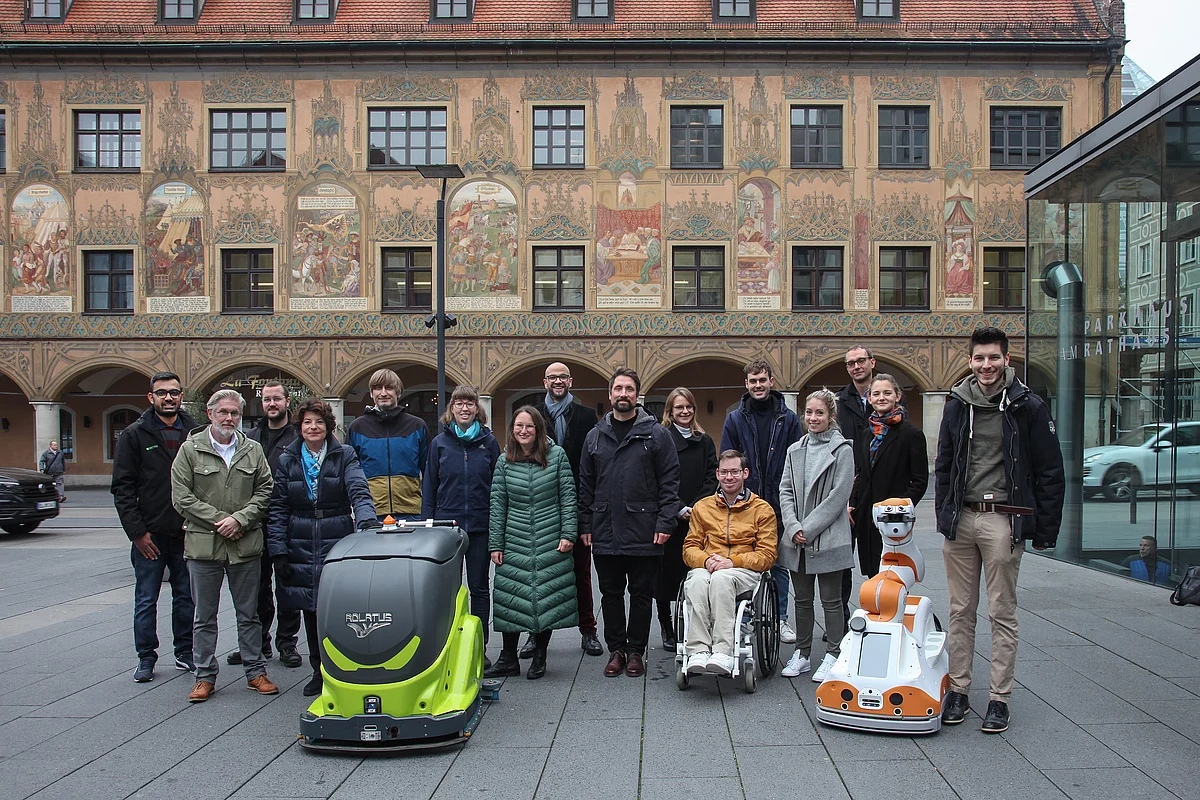 [Translate to English:] Gruppe von Menschen mit zwei Servicerobotern