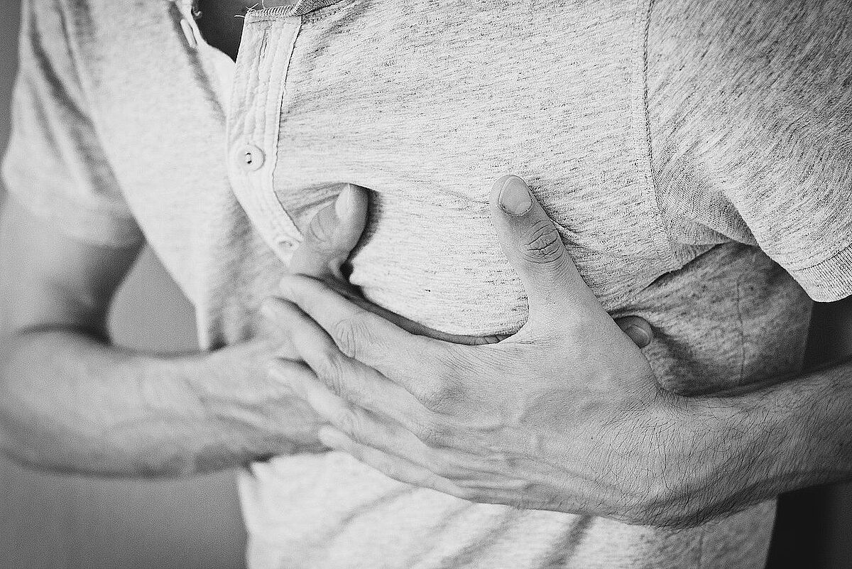 Mann greift sich an Brust