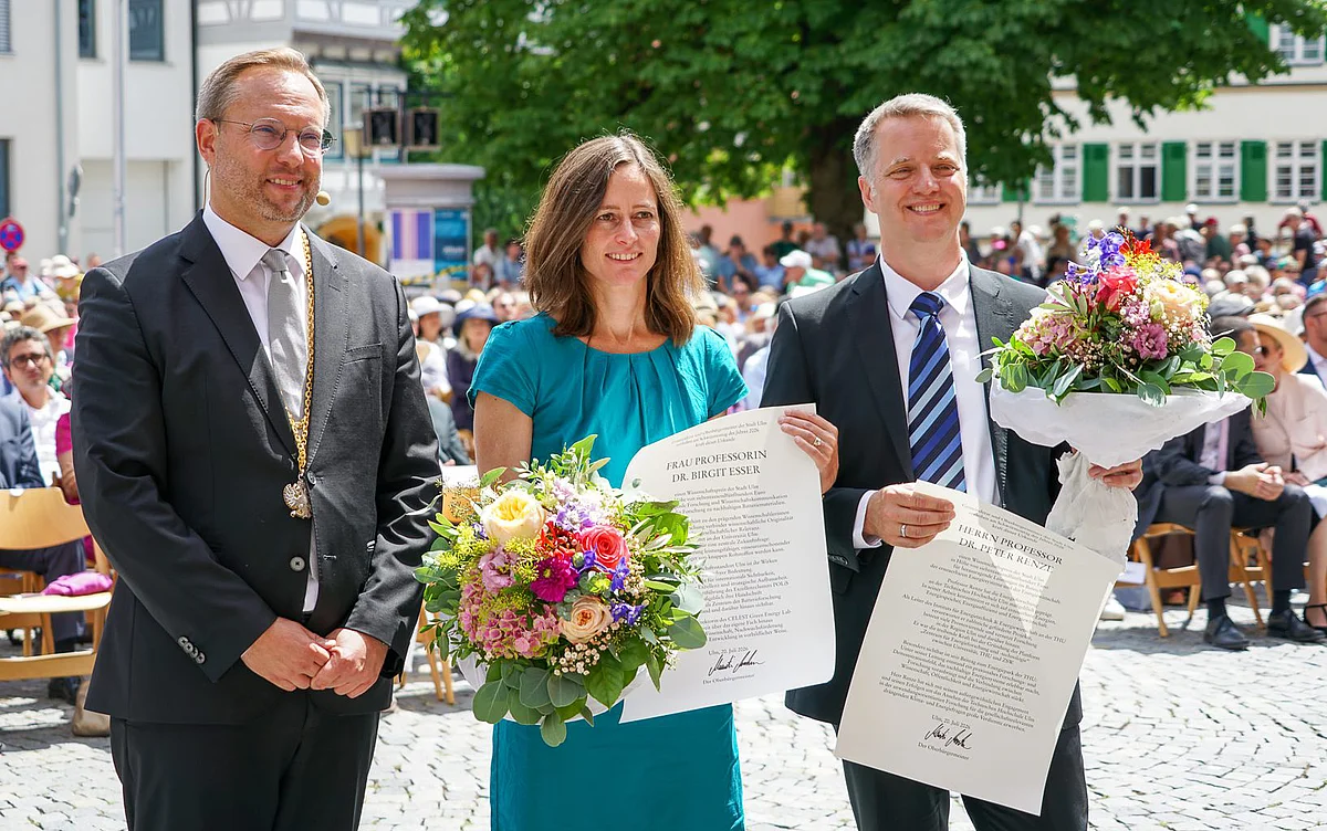 Gruppenbild mit (v.l.) OB Martin Ansbacher, Prof. Birgit Esser und Prof. Renze  auf dem Weinhof. Esser und Renze haben Blumensträuße und Urkunden in der Hand