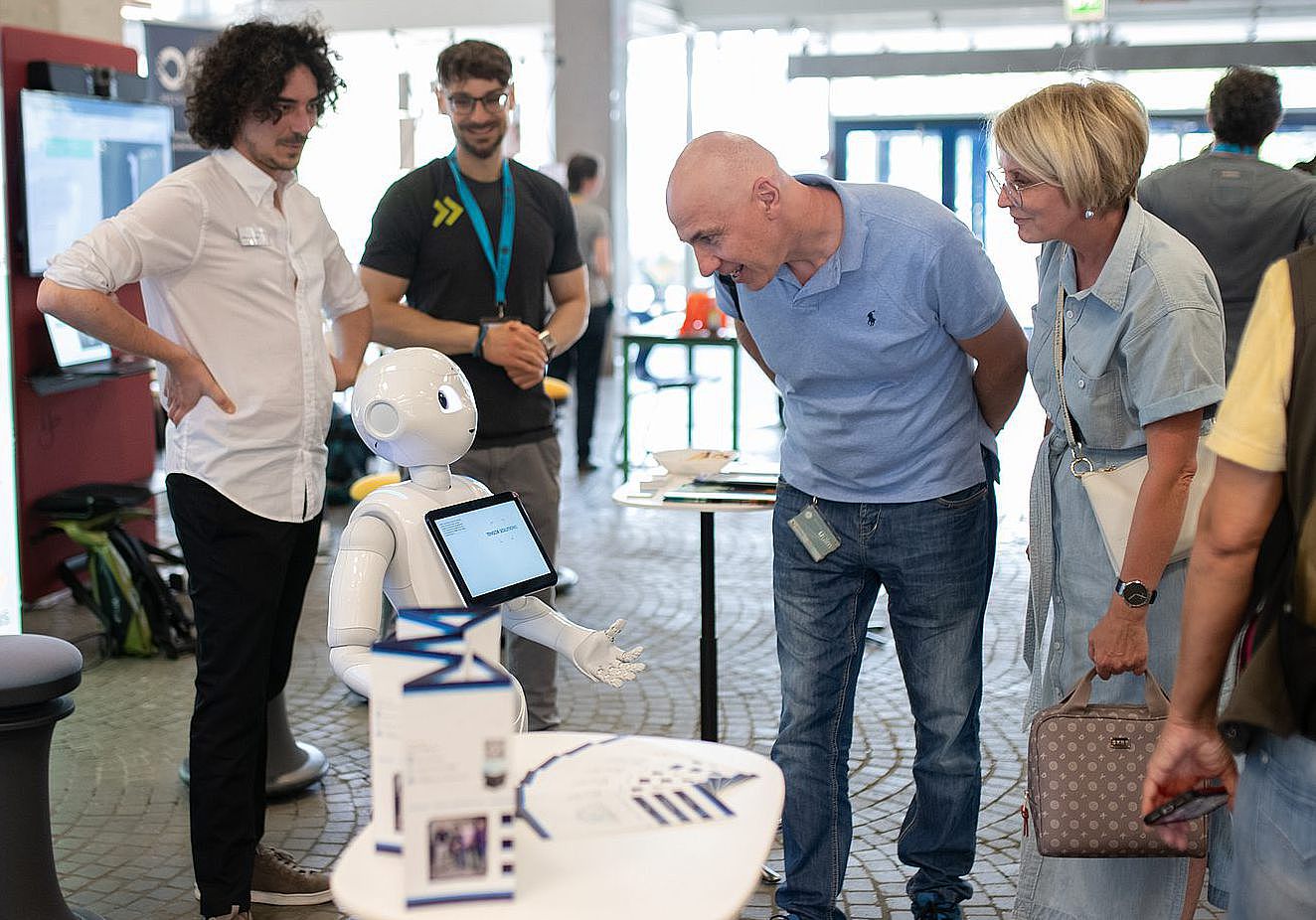 Stand des Entrepreneurs Campus beim Langen Abend der Wissenschaft 2024. Menschen interagieren mit einem Roboter.