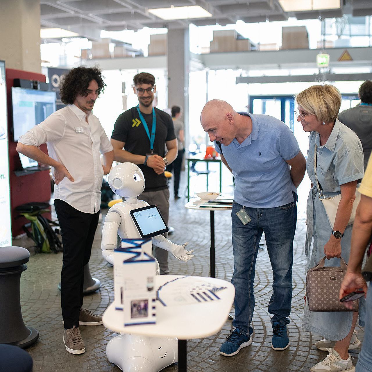 Stand des Entrepreneurs Campus beim Langen Abend der Wissenschaft 2024. Menschen interagieren mit einem Roboter.