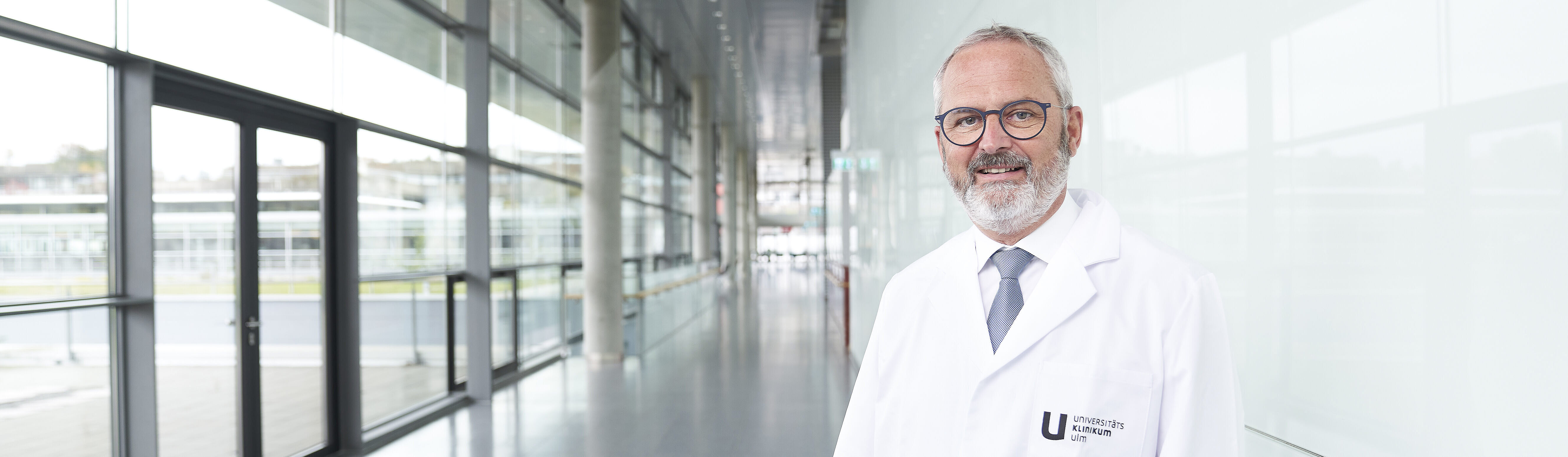Prof. Florian Gebhard in medizinischer Berufsbekleidung auf einem langen Flur