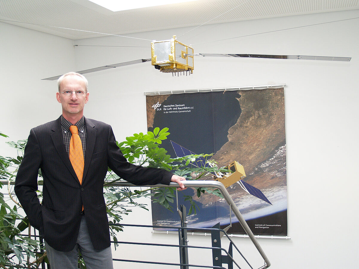 DLR-Forscher Uwe-Carsten Fiebig (im Hintergrund ein Satellitenmodell)