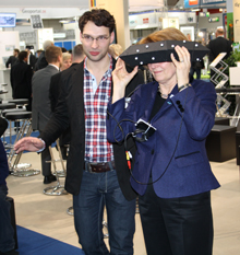 Blick mit ImmerSight in die dreidimensionale virtuelle Welt: Fabian Weiss, einer der drei beteiligten Ulmer Nachwuchswissenschaftler, erklärt einer Interessentin auf der CeBIT die neu entwickelte 3D-Technologie 