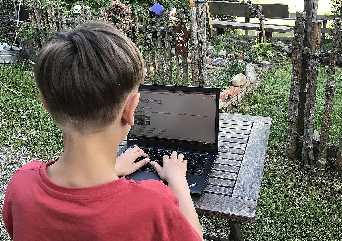 Stimmungsbild zeigt Kind mit Laptop von hinten