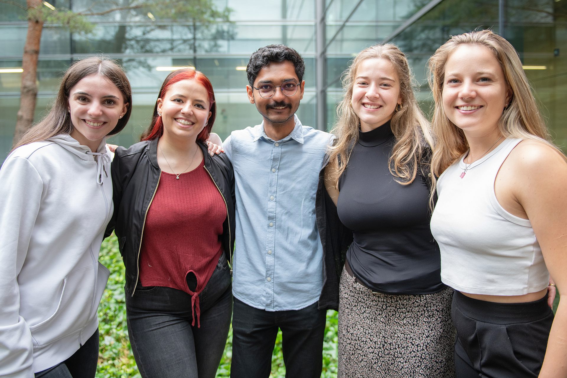 Studierende stehen nebeneinander in einer Gruppe und lächeln in die Kamera
