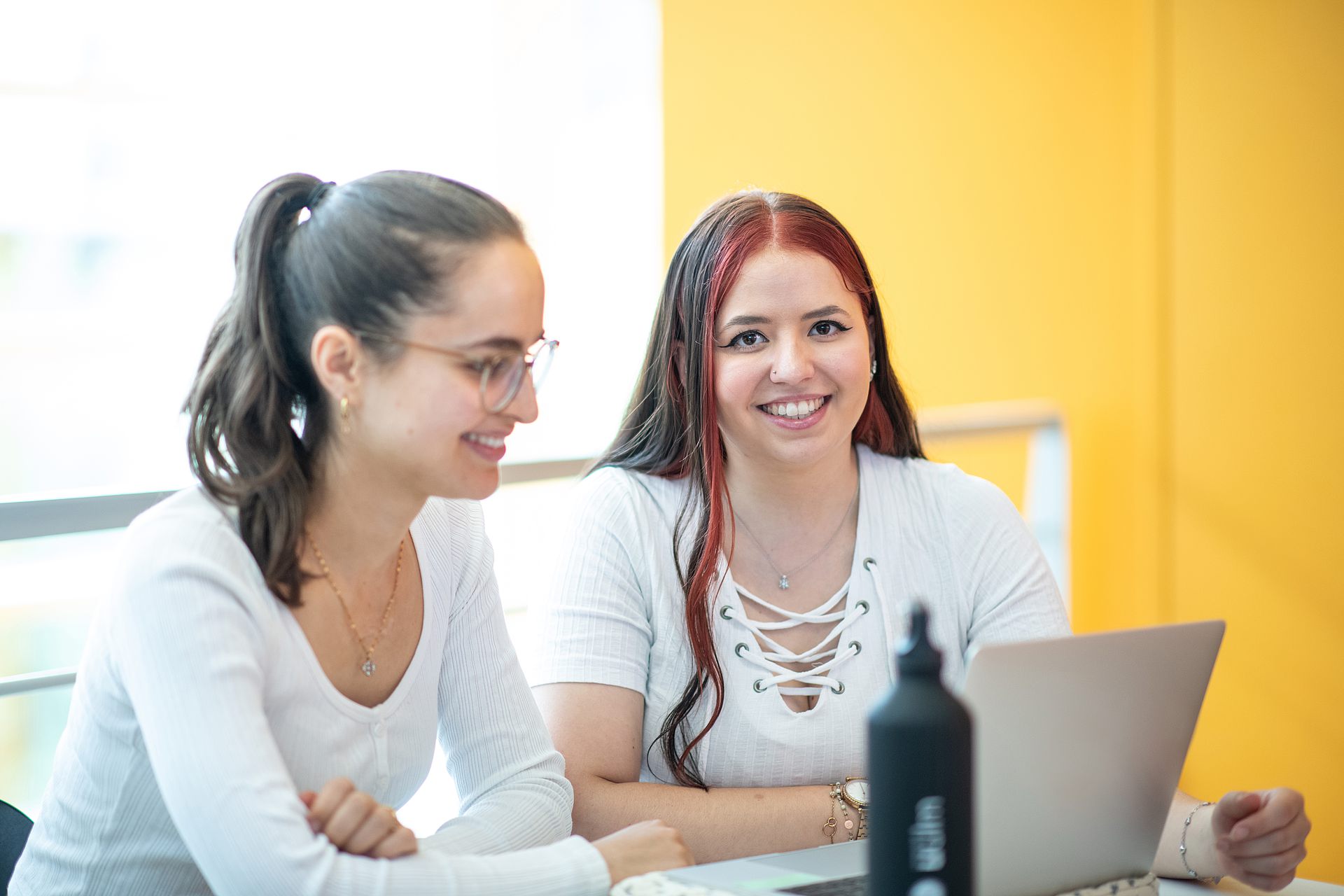 Zwei Studierende sitzen mit einem Laptop am Tisch