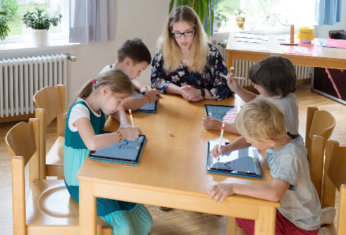 Kinder beim Schreiben mit einem digitalen Stift auf der Oberfläche eines Tablet Computers 