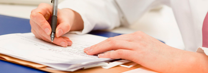 A person edits a document with a pen at a desk - Symbolic Picture for Filling out Forms.