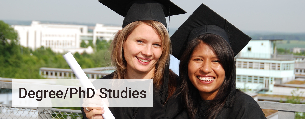 Students from different origins with cap and gown and diploma