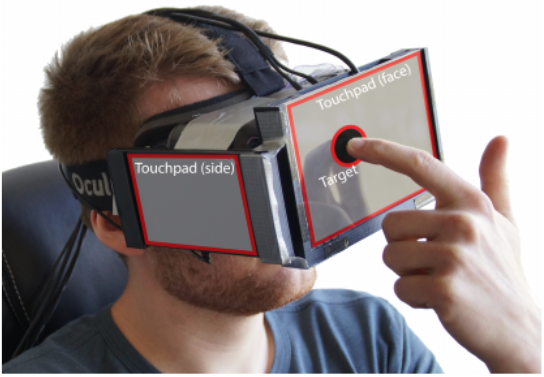 Photographie: Mensch, der auf einen Touchmonitor deutet, der an der Frontseite einer VR-Brille befestigt ist
