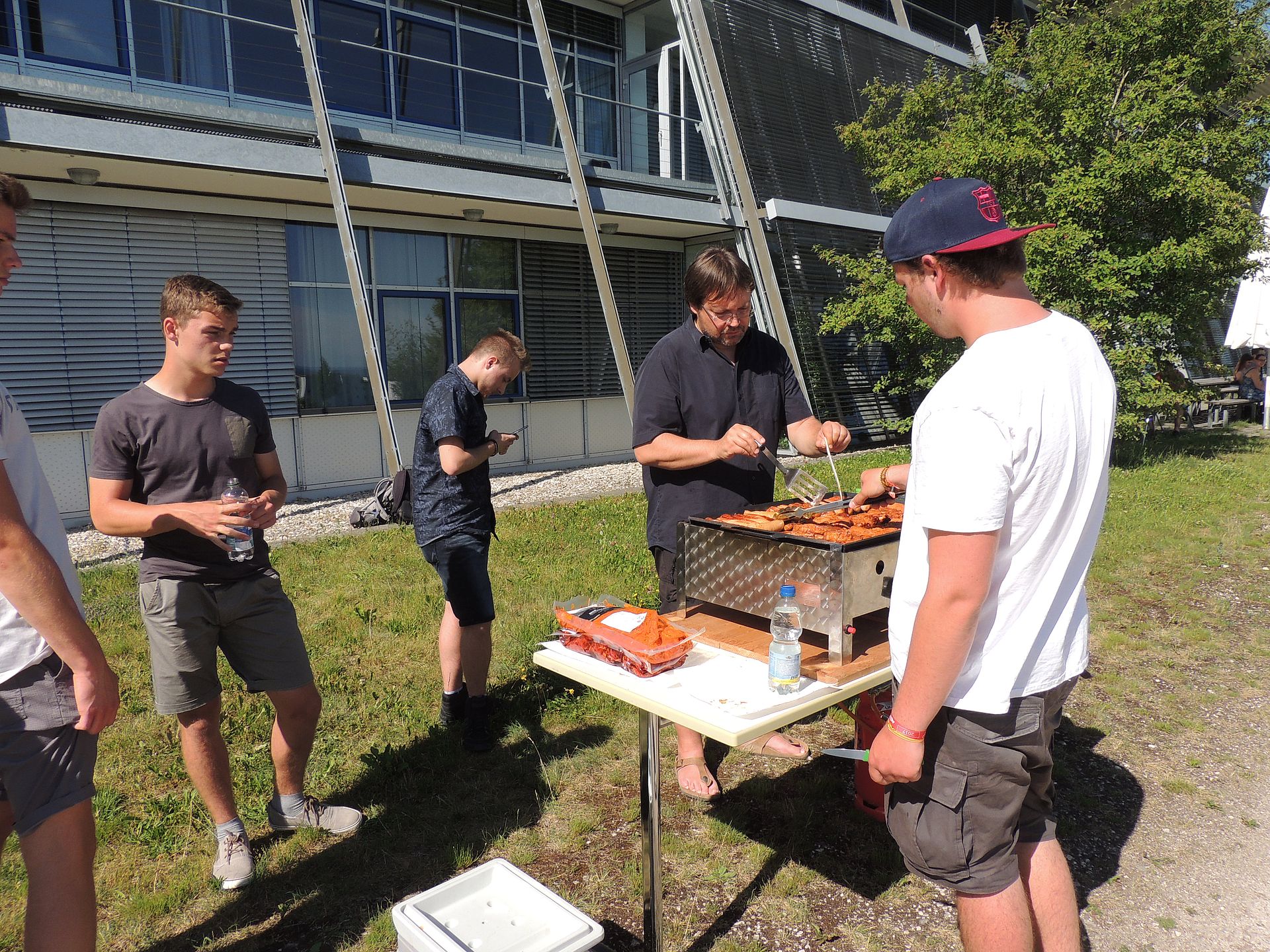 Studierende stehen um einen Grill vor der Hochschule 