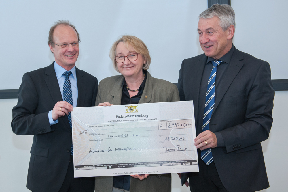 The Minister for Science, Research and Art, Theresia Bauer hands over a cheque in support of the newly founded Center for Trauma Research (ZTF) (left: President Prof. Dr. Michael Weber, right: Dean of the Medical Faculty Prof. Dr. Thomas Wirth).