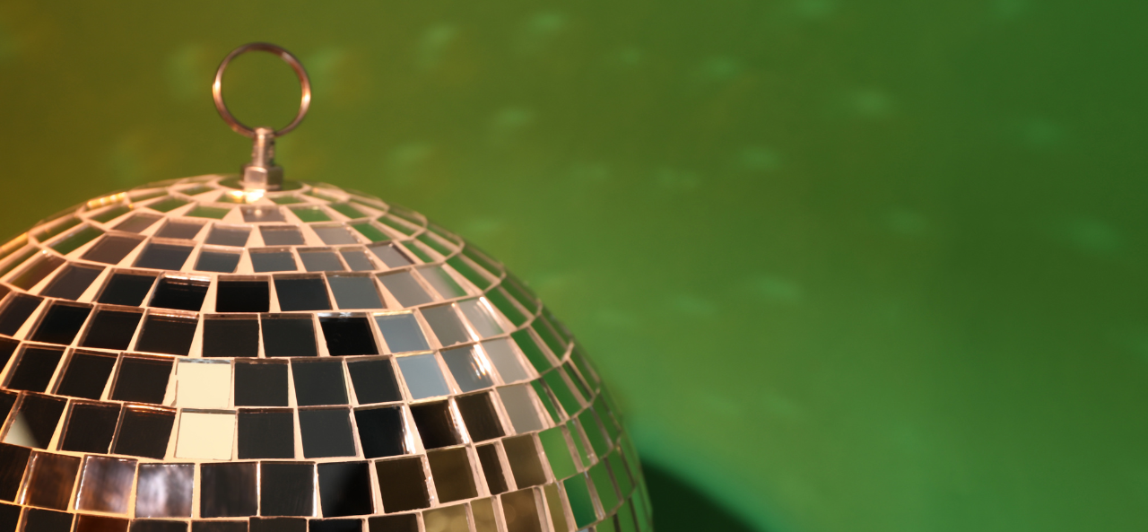 Disco ball in front of green wall.